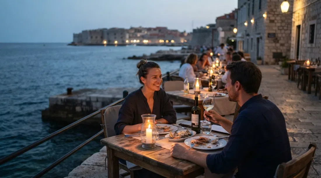 Terraza de piedra del Restaurant Levanat al anochecer sobre el agua en Šetalište Nika i Meda Pucića 15, luz de velas en las mesas y el mar justo al lado