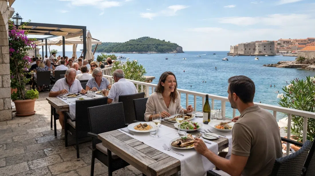 la terraza junto a la orilla de Prora, Hotel Excelsior, con Lokrum visible tras el agua y un ambiente de comida veraniega centrada en el pescado